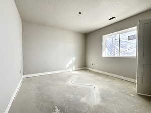 Spare room with concrete flooring, a textured ceiling, and baseboards