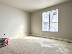 Unfurnished room with visible vents, a textured ceiling, and baseboards