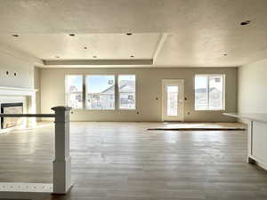 Unfurnished living room with a textured ceiling, a fireplace, and wood finished floors