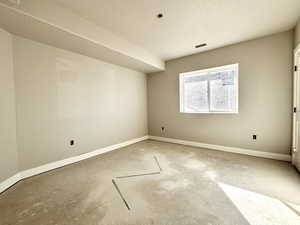 Unfurnished room with visible vents, concrete floors, baseboards, and a textured ceiling