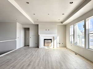 Unfurnished living room featuring a textured ceiling, light wood-type flooring, and a fireplace