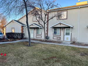 View of property with a front lawn and stucco siding