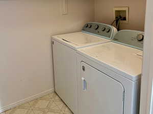 Laundry area featuring laundry area, light floors, washing machine and dryer, and baseboards