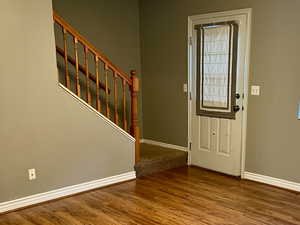 Foyer entrance featuring stairs, wood finished floors, visible vents, and baseboards