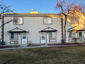 Multi unit property featuring a front lawn and stucco siding