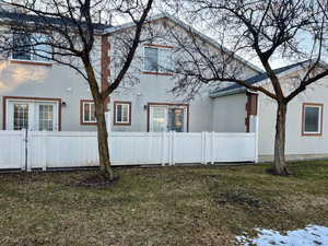 View of side of property with a yard, a fenced front yard, a gate, and stucco siding