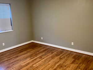 Empty room featuring a textured ceiling, baseboards, and wood finished floors