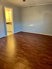 Unfurnished room featuring ceiling fan, ornamental molding, wood finished floors, and baseboards