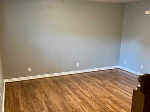 Unfurnished room featuring a textured ceiling, wood finished floors, and baseboards