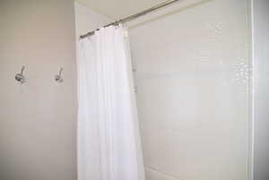 Bathroom #1 featuring curtained and tiled tub/shower surround.