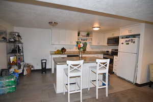 In-law apartment Kitchen with appliances with stainless steel finishes, white cabinetry, granite counters, and open shelves