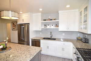 Kitchen featuring stainless steel appliances, light granite counters, composite sink, and white cabinetry