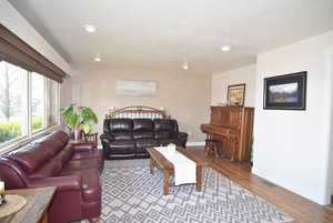 Living room with recessed lighting, hardwood finished floors, large windows and fireplace (behind the couch)