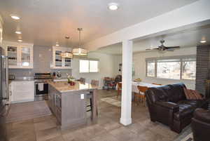 Kitchen featuring tasteful backsplash, glass insert cabinets, a breakfast bar, granite counter tops, open floor plan, and stainless steel appliances