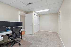 Office area featuring visible vents, a paneled ceiling, and baseboards