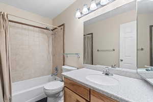 Full bath with toilet, shower / tub combo with curtain, and vanity