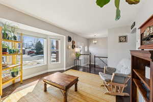 Sitting room with visible vents, wood finished floors, an upstairs landing, and baseboards