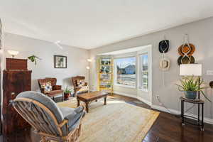 Living area with wood-type flooring, visible vents, and baseboards