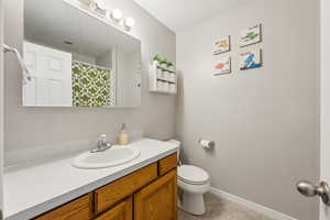 Bathroom with baseboards, toilet, tile patterned floors, curtained shower, and vanity