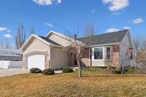 Ranch-style house with brick siding, concrete driveway, a front yard, fence, and a garage