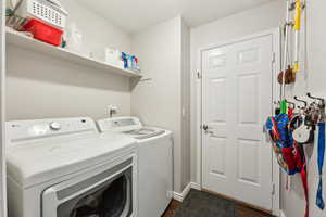 Laundry room with laundry area, washing machine and dryer, dark wood finished floors, and baseboards