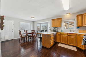 Kitchen with a peninsula, a kitchen bar, a sink, and dark wood finished floors