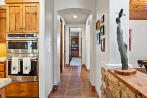Hallway with dark tile patterned flooring, arched walkways, and baseboards