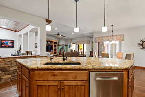 Kitchen with a sink, a kitchen island with sink, brown cabinets, and open floor plan