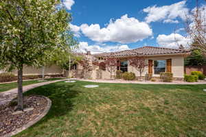 View of front of property featuring a front lawn, fence, stone siding, stucco siding, and a tiled roof