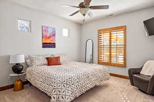 Carpeted bedroom with baseboards, a ceiling fan, and visible vents