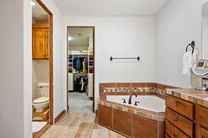 Bathroom with a garden tub, toilet, and a spacious closet