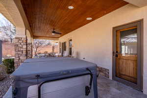 View of patio / terrace featuring fence, outdoor dining space, ceiling fan, and a hot tub