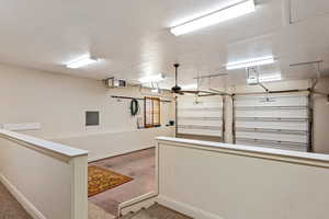 Garage featuring a ceiling fan, baseboards, and a garage door opener
