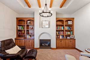 Sitting room featuring baseboards, carpet, a notable chandelier, and beamed ceiling