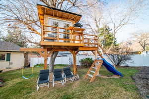 View of tree house featuring a fenced backyard and a lawn