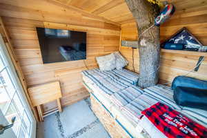 Bedroom with vaulted ceiling, wood walls, and wood ceiling (tree house)