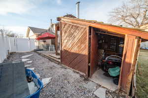 View of home's exterior with an outbuilding, fence, and a gate