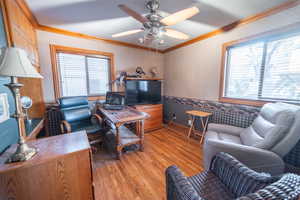 Office space with ornamental molding, wainscoting, light wood finished floors, plenty of natural light, and wallpapered walls