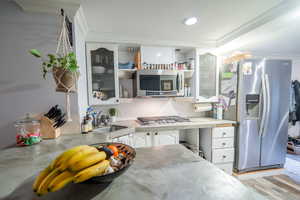 Kitchen featuring stainless steel appliances, a sink, white cabinets, light countertops, and crown molding