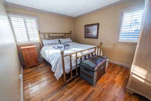 Bedroom with light wood-style flooring, multiple windows, baseboards, and crown molding