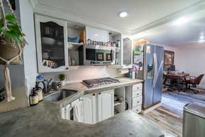 Kitchen with open shelves, stainless steel appliances, ornamental molding, white cabinets, and a sink