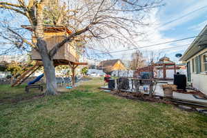 View of yard featuring a tree house and fence