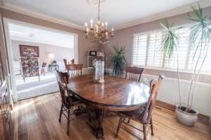 Dining area with hardwood / wood-style flooring, a notable chandelier, and crown molding