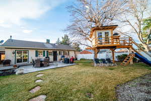 Rear view of house with a tree house, brick siding, a lawn, fence, and a deck