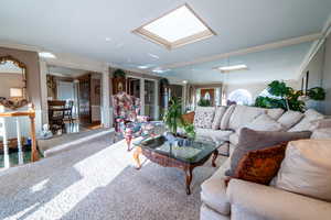 Living room featuring a skylight, decorative columns, and crown molding