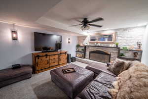 Carpeted living room with ceiling fan and a fireplace