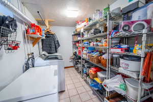 Laundry room with light tile patterned floors, laundry area, a textured ceiling, and washer and dryer