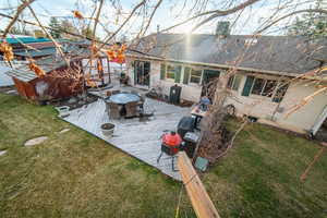 Back of house featuring a deck, brick siding, a shingled roof, a yard, and a chimney