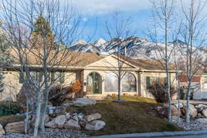 Ranch-style house with a mountain view, a front lawn, and stucco siding