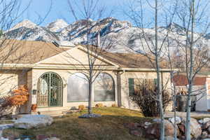 Exterior space featuring a shingled roof, a front yard, a mountain view, and stucco siding